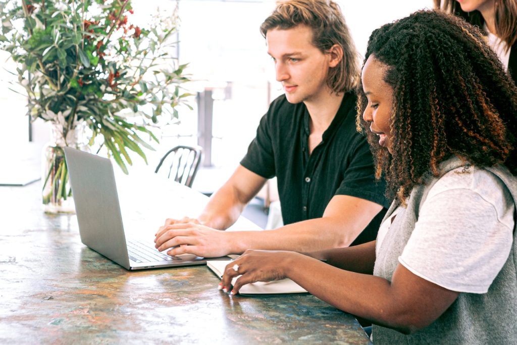 man and woman working on laptop together in marketing office