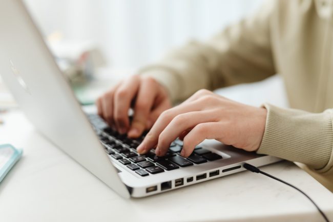 man's hands typing on laptop