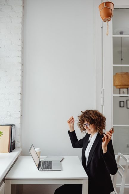 woman sitting at desk in front of laptop cheering